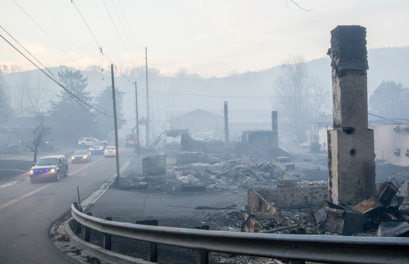 Law enforcement vehicles drive through the smoke near structures destroyed by wildfires in Gatlinburg, Tennessee. (Image: AP)